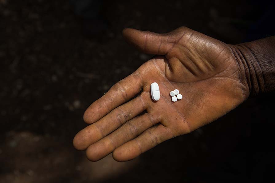A hand holding two pills