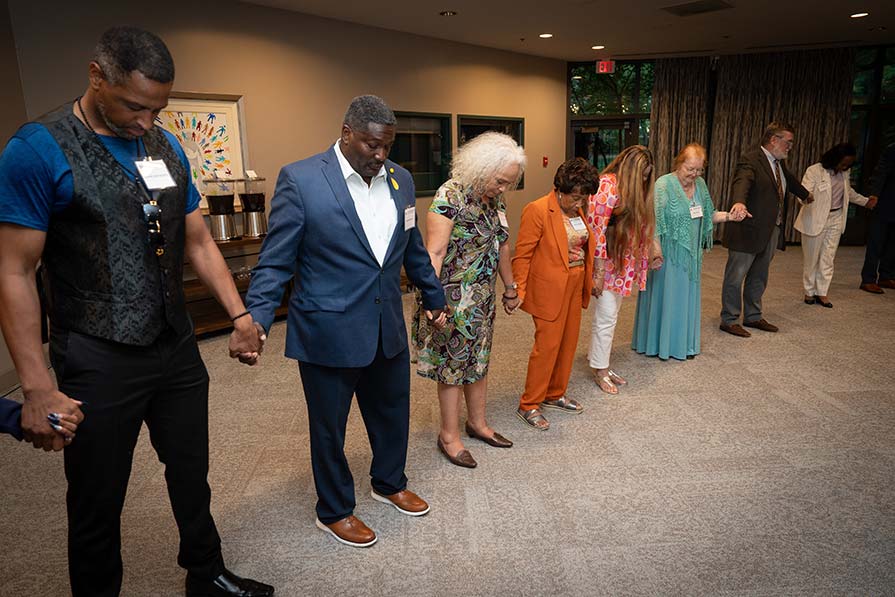 A group holds hands in prayer.